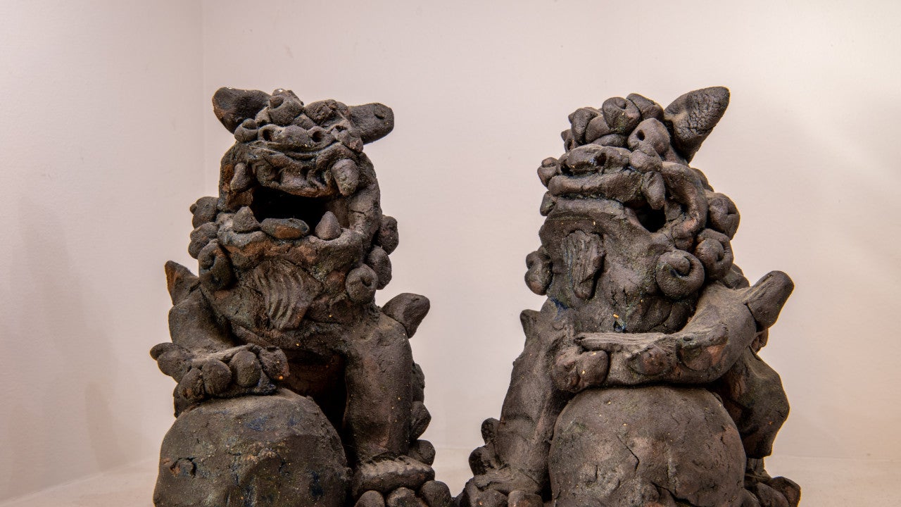 Two shisa, Okinawan traditional statues of animals similar to dogs. The right one has its mouth closed while the left has its mouth open.