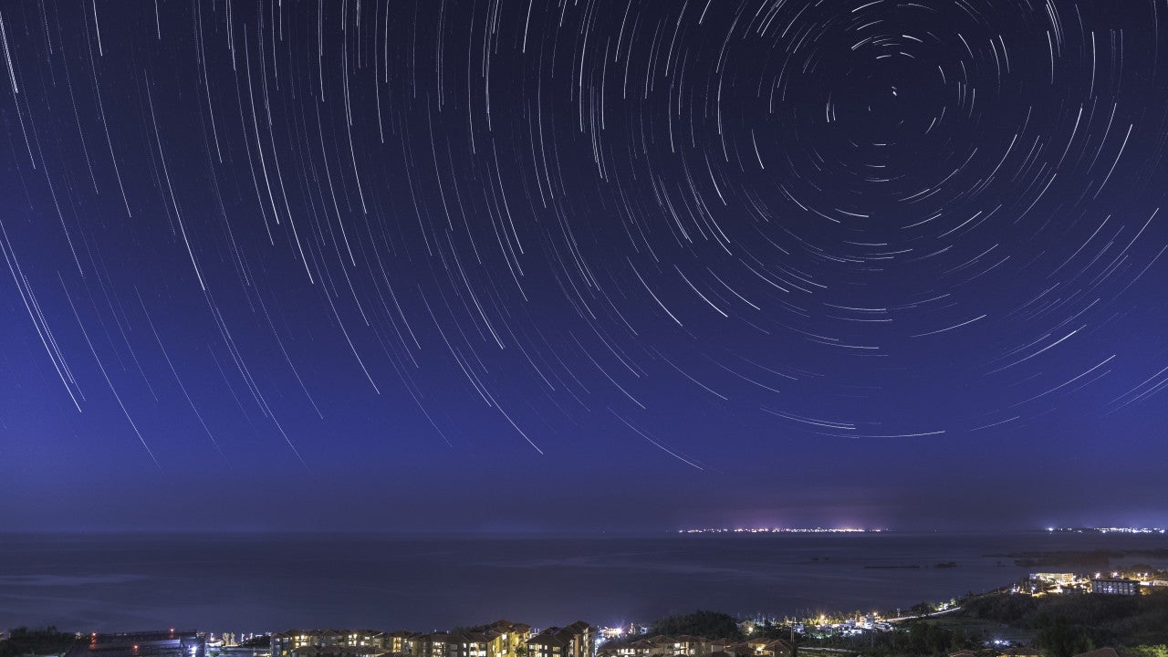 Time-lapse night photo of stars moving over Tancha Bay and OIST campus