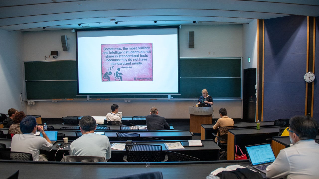 auditorium with slide stating that sometimes the most brilliant and intelligent students do not shine in standardized tests because they do not have standardized minds