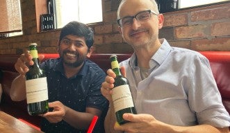 2 people holding wine bottles