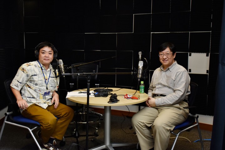 Nagahama and Kitano seated at a round table in the audio booth.