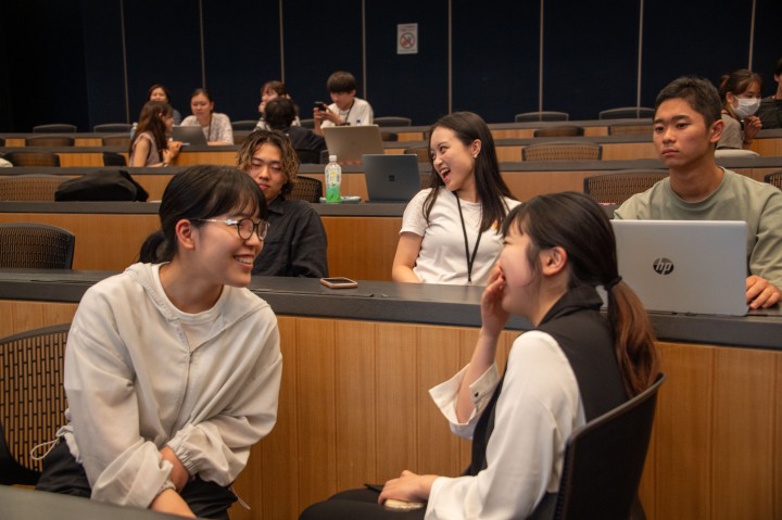 A number of participnts sit in a seminar room laughing and talking to each other.