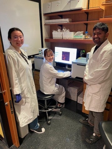 Student from Keio University with lab members in white coat