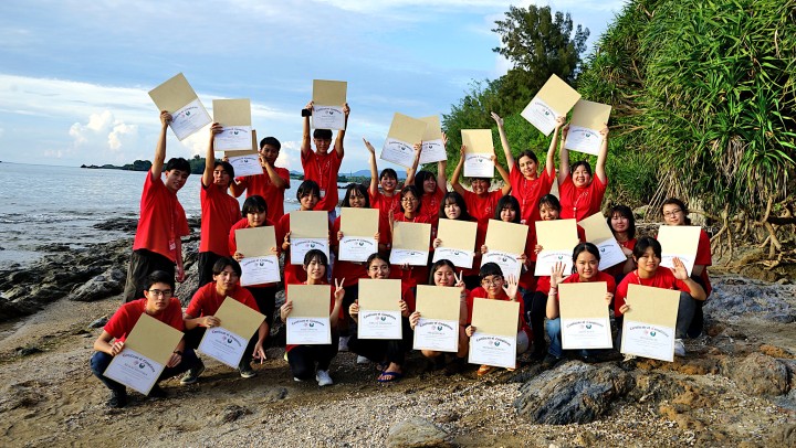 students holding certificate on the beach