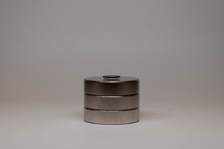 A profile view of a black graphite disk floating above a stack of three, shiny magnets. One can clearly see the separation between magnets and the disk.
