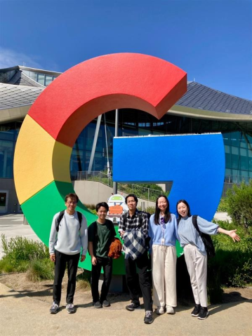 Google Visitor Experienceのカラフルで大きなGoogleロゴの前で撮影した集合写真。太陽の下で笑顔を見せる5人。