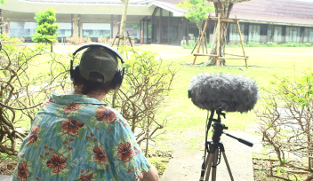 DJ Nick Luscombe with mic and headphones, from behind.