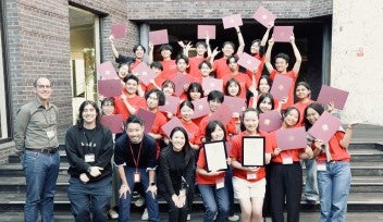OISTの赤い Tシャツを着て、サイエンスチャレンジ2025の修了証を手にした学生たちと主催者