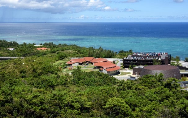 Red-roofed building amind greenary and blue ocean