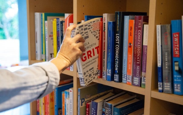A hand taking a book from a bookshelf