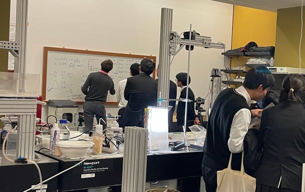 Jack writing on a white board in front of students.