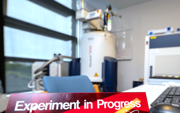 a sign saying Experiment in Progress on a desk and a machine on the background