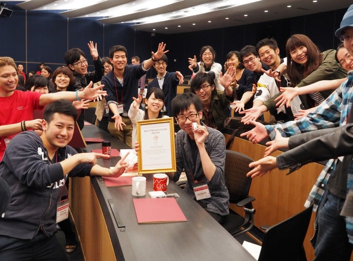 Students around a certificate in a frame